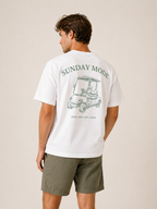 Man wearing a white t-shirt with 'Sunday Mode' graphic on the back, standing against a beige background.